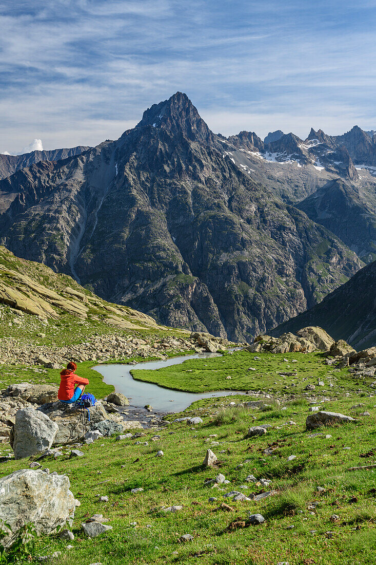 Frau beim Wandern sitzt auf Felsblock und blickt auf Aiguille du Plat de la Selle, am Lac des Bèches, Ecrins, Nationalpark Ecrins, Dauphine, Dauphiné, Hautes Alpes, Frankreich