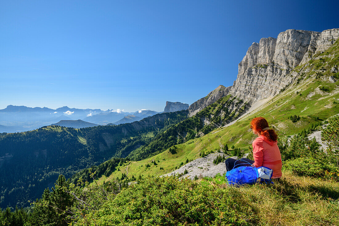 Woman while hiking sits on, paragraph and overlooks the mountain scenery, the Grand Veymont, Vercors, Dauphine, Dauphine, Isère, France