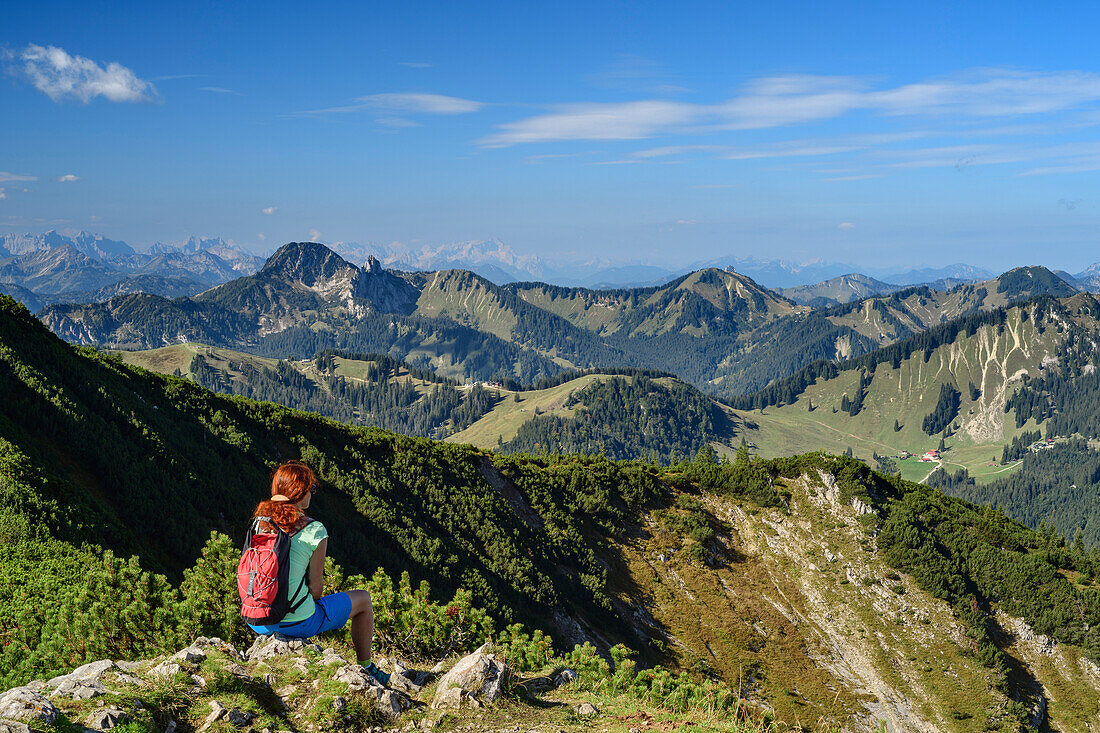 Frau beim Wandern sitzt auf Wiesenabsatz und blickt auf Bayerische Alpen, Jägerkamp, Mangfallgebirge, Bayerische Alpen, Oberbayern, Bayern, Deutschland