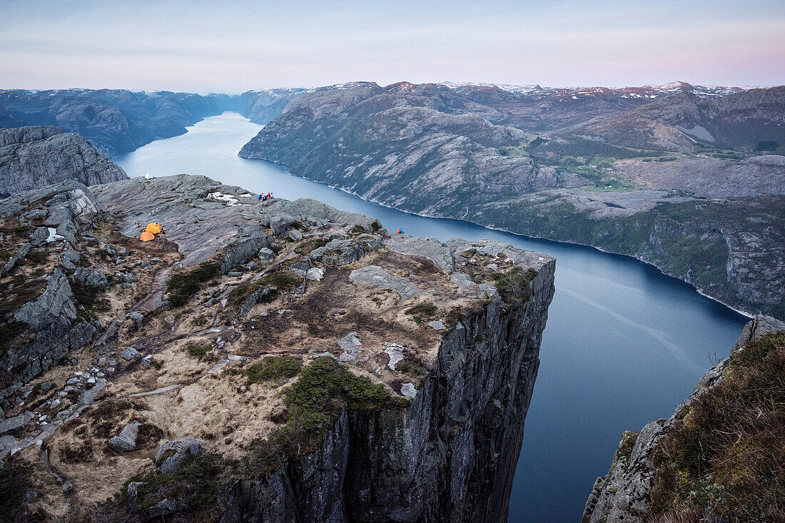 Wanderer sitzen an Felskante beim Preikestolenund genießen den Ausblick auf den Lysefjord, Provinz Rogaland, Norwegen, Skandinavien, Europa