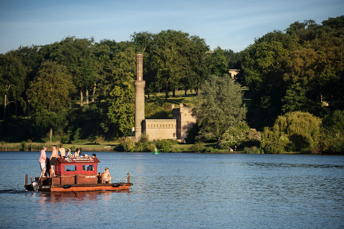 group of people in swimsuits relax at motorized float, view from Glienicke Bridge at royal garden of Babelsberg, Potsdam, Brandenburg, Germany