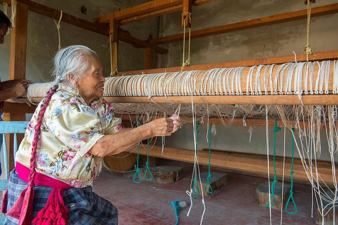 An old Zapotek woman is preparing a loom for weaving a carpet at a weavers home studio in Teotitlan del Valle, a small town in the Valles Centrales Region near Oaxaca, southern Mexico.
