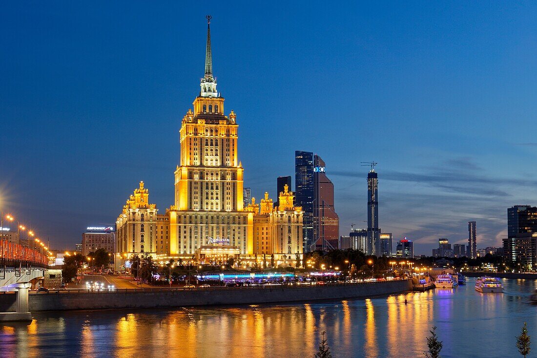 Radisson Royal Hotel Stalinist style high-rise building on Moskva River illuminated at dusk. Moscow, Russia.