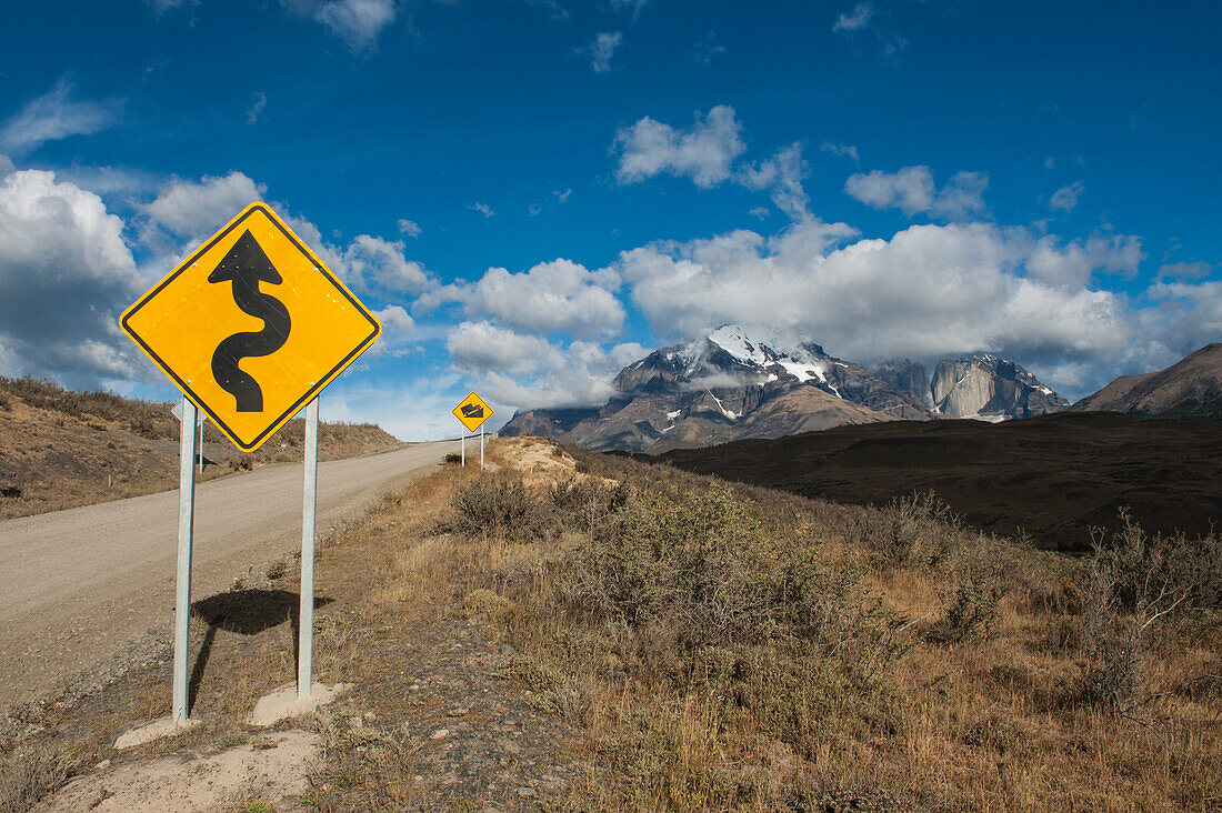 Schilder weisen auf steile kurvige Straßen durch die hügelige Landschaft hin, Nationalpark Torres del Paine, Chilena Magallanes y de la Antartica, Patagonien, Chile, Südamerika