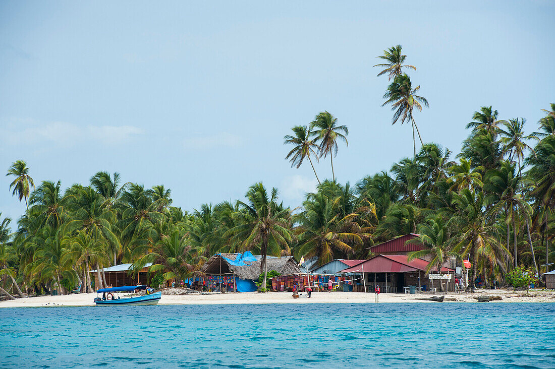 Huts and a volleyball net are clustered among palm trees on one of the tiny islands, San Blas Islands, Panama, Caribbean