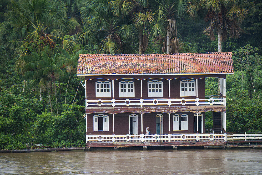 A noble looking two-storey house with a two-tiered wrap-around porch on two sides stands on the shore of the Amazon river, Breves Channels, near Belem, Para, Brazil, South America