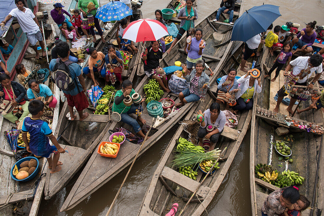 Kanus, die mit Früchten, Andenken und anderen Produkten zum Tauschen gefüllt sind, legen hinter einem Expeditions-Kreuzfahrtschiff an, das am Amazonas vor Anker liegt, Pebas (auch Pevas), nahe Iquitos, Maynas, Peru, Südamerika