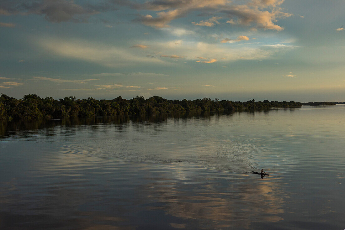 Ein einsames Kanu paddelt am späten Nachmittag auf dem Amazonas über die Wasserstraße, Jutai, Amazonas, Brasilien, Südamerika
