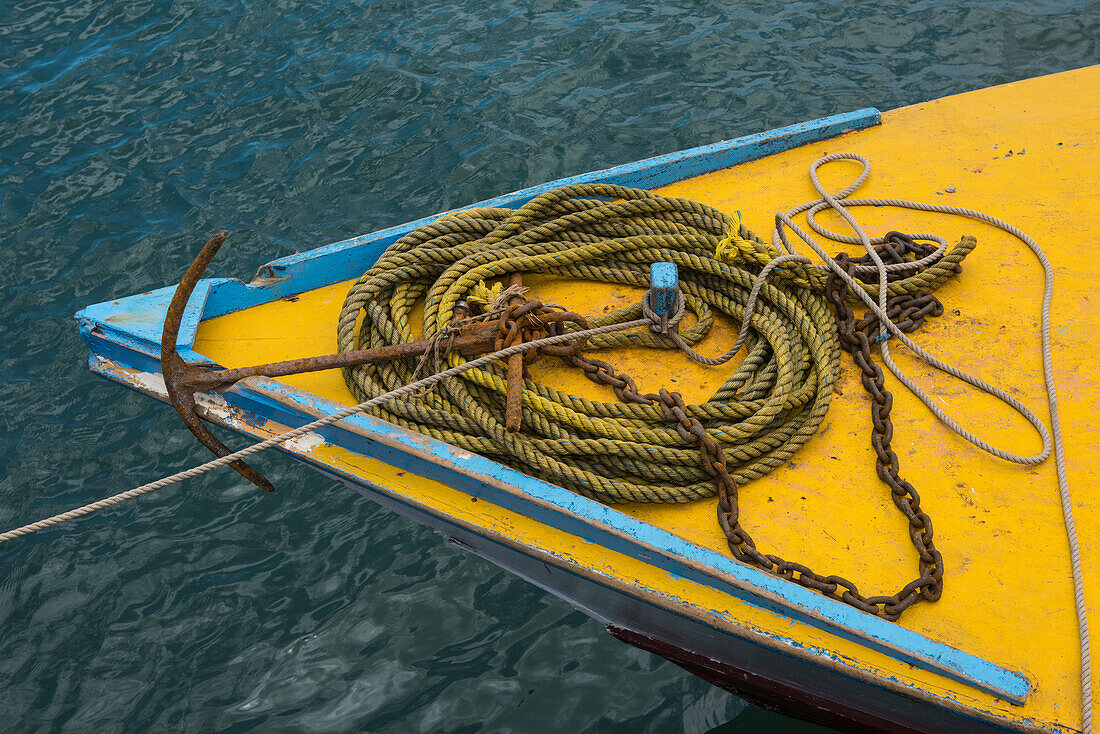 Ein gelb-blauer Bug eines kleinen Schiffes ist mit einem gelben Seil überzogen, das an einer rostigen Kette und einem Anker befestigt ist, Lautoka, Viti Levu, Fidschi, Südpazifik