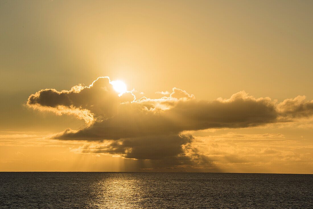 Die späte Nachmittagssonne bricht durch Gewitterwolken und erzeugt ein warmes orange-gelbes Licht, Bora Bora, Gesellschaftsinseln, Französisch-Polynesien, Südpazifik