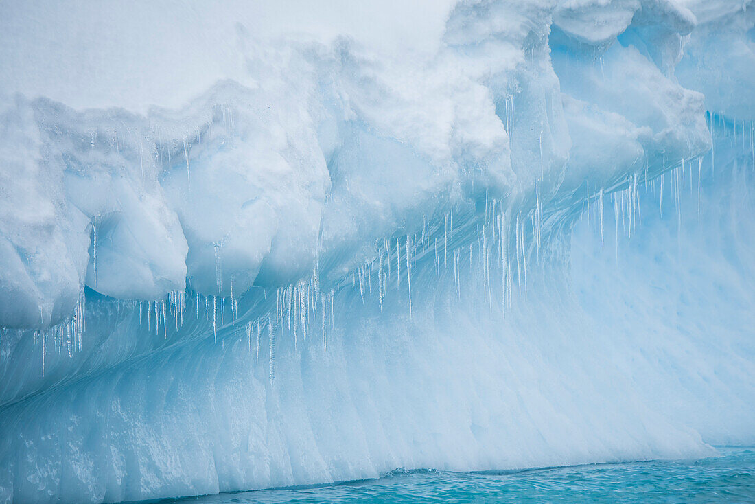 Am Rande eines großen Eisbergs bilden sich zahlreiche dünne Eiszapfen, Dorian Bay, Wiencke Island, Antarctica