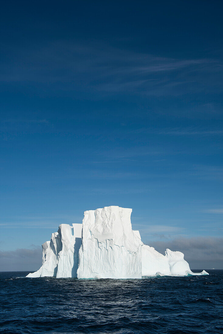 Ein massiver Eisberg schwebt auf offenem Meer über einem blauen Himmel, nahe South Shetland Islands, Antarktis