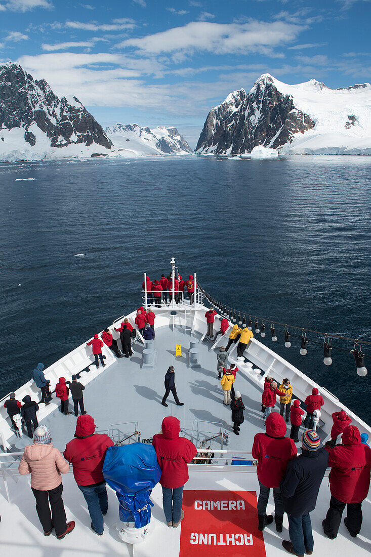 Die Passagiere von Expeditions Kreuzfahrtschiff MS Bremen (Hapag-Lloyd Kreuzfahrten) versammeln sich auf den Vorderdecks während sich das Schiff einem engen Seeweg nähert, Lemaire-Kanal, nahe Graham Land, Antarktis