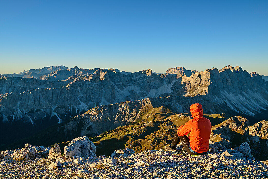 Mann beim Wandern sitzt am Peitlerkofel und blickt auf Dolomiten mit Marmolada, Sellagruppe, Langkofel und Geislergruppe, vom Peitlerkofel, Dolomiten, UNESCO Welterbe Dolomiten, Südtirol, Italien