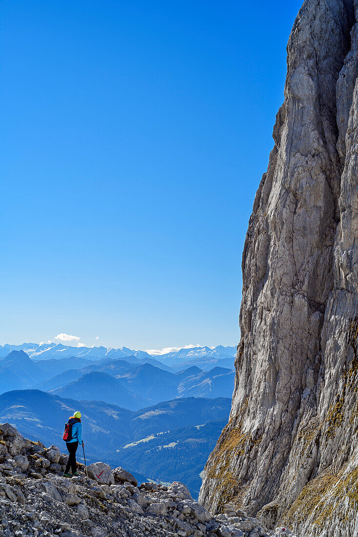 Woman hiking descending from Ellmauer Tor, view to rock wall in Kaiser range, Wilder Kaiser, Kaiser range, Tyrol, Austria