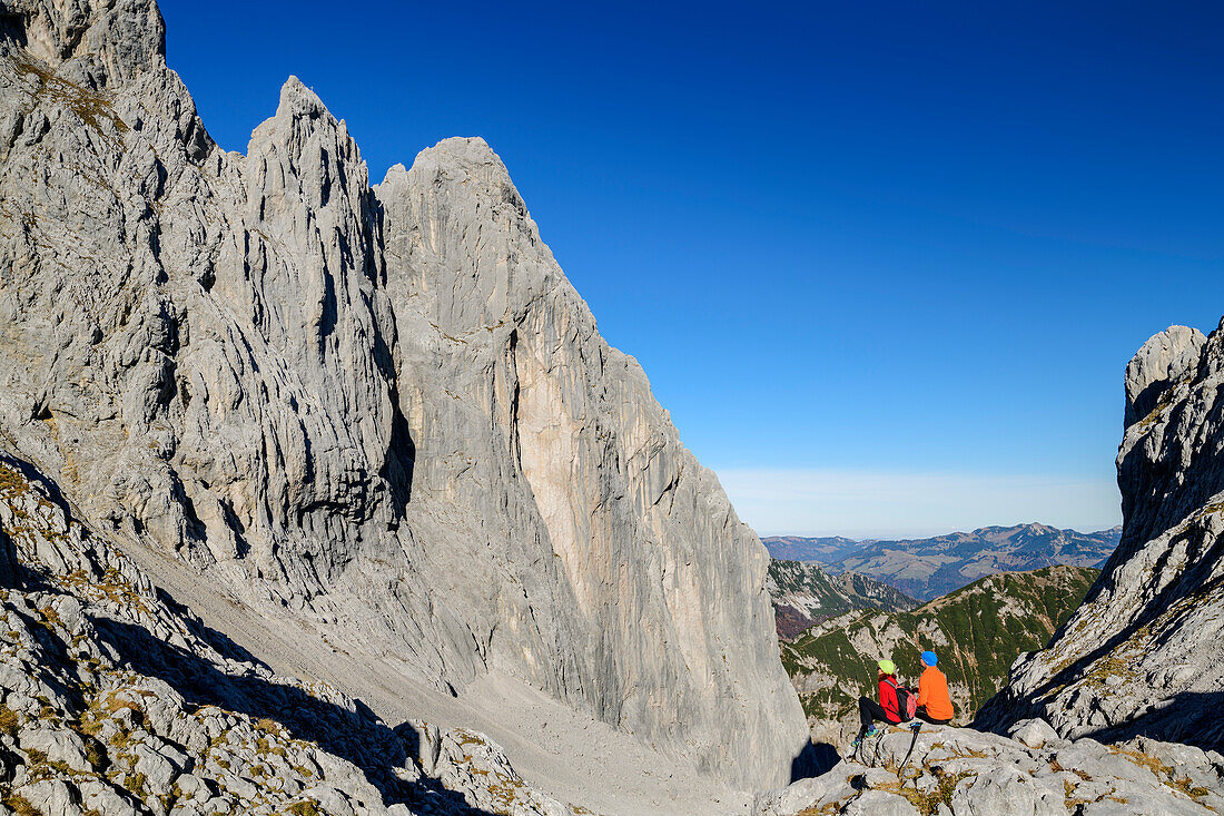 Mann und Frau beim Wandern sitzen im Ellmauer Tor und blicken auf Christaturm und Fleischbank, Ellmauer Tor, Wilder Kaiser, Kaisergebirge, Tirol, Österreich