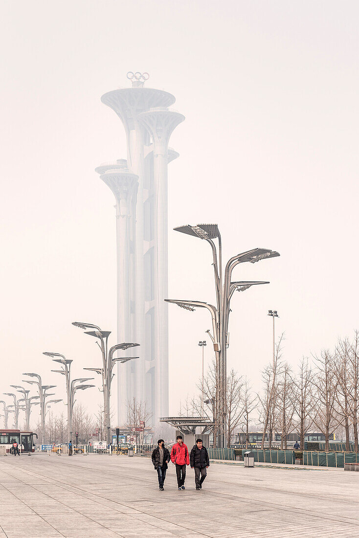 Chineses men (some with air mask) walk through park, Olympic Tower wrapped in heavy air pollution at background, Olympic Green, Beijing, China, Asia