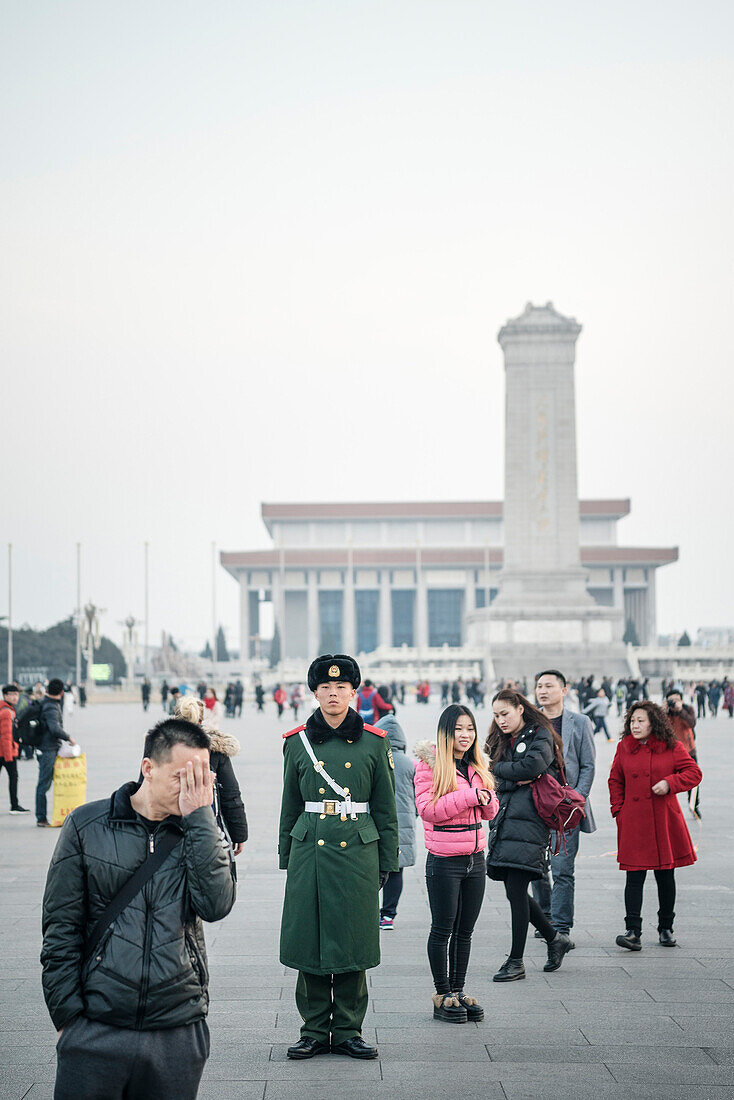 guardman stands still in front of People’s Heroes Monument and the Mao Zedong Memorial Hall surrounded by people, Tiananmen Square, Beijing, China, Asia