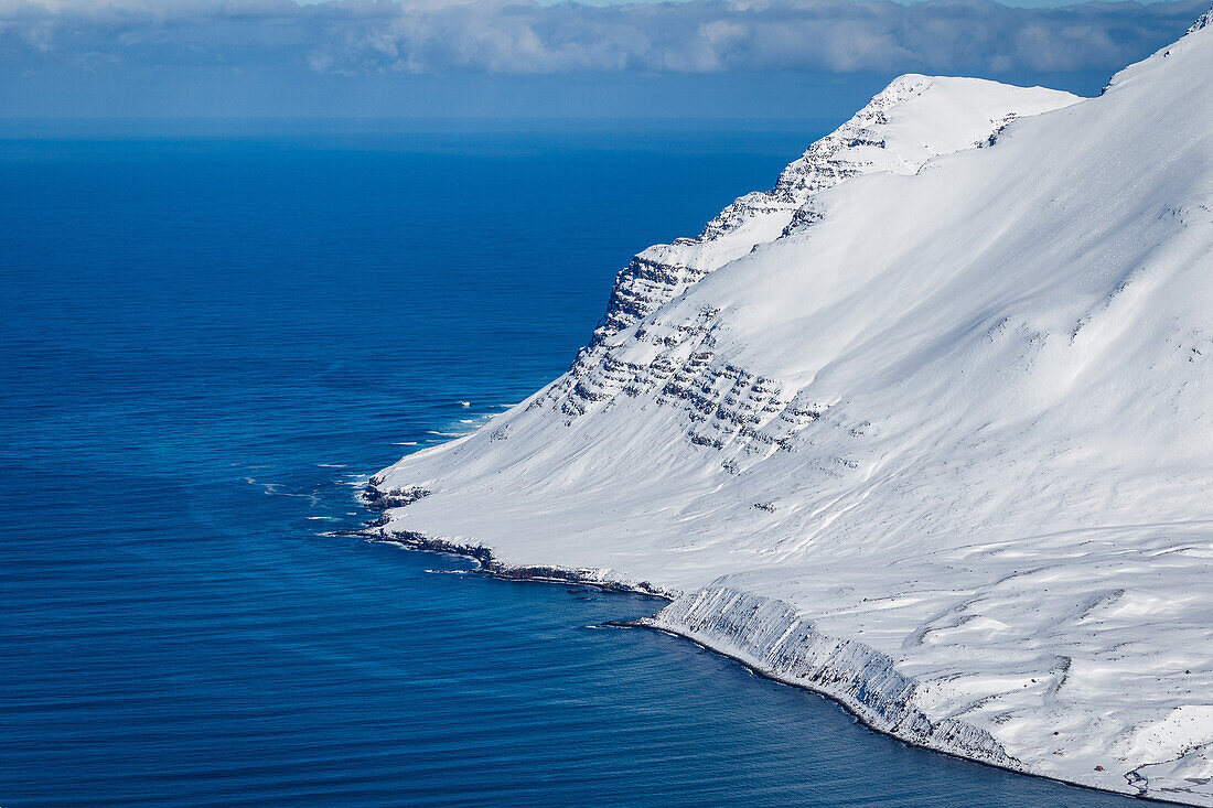 Verschneite Hänge enden im Meer, Tröllaskagi, Island, Skandinavien