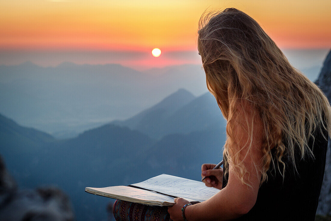 Young woman at the summit, writing into a book, Scheffauer, Wilder Kaiser, Tyrol, Austria