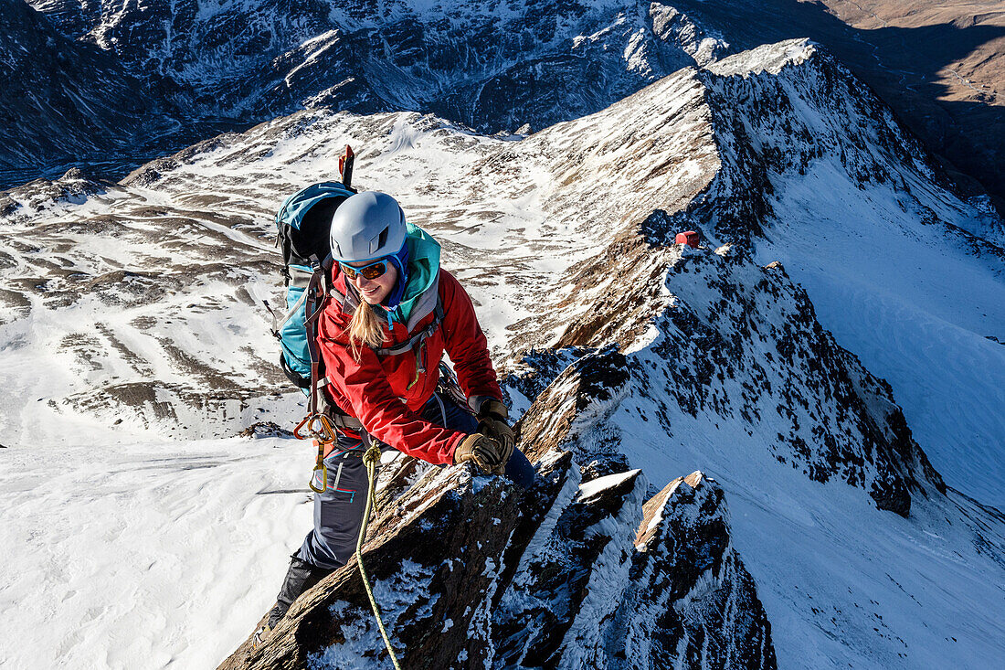 Junge, weibliche Alpinistin klettert an einem Grat im Winter, Piz Tresero, Valfurva, Lombardei, Südtirol, Italien