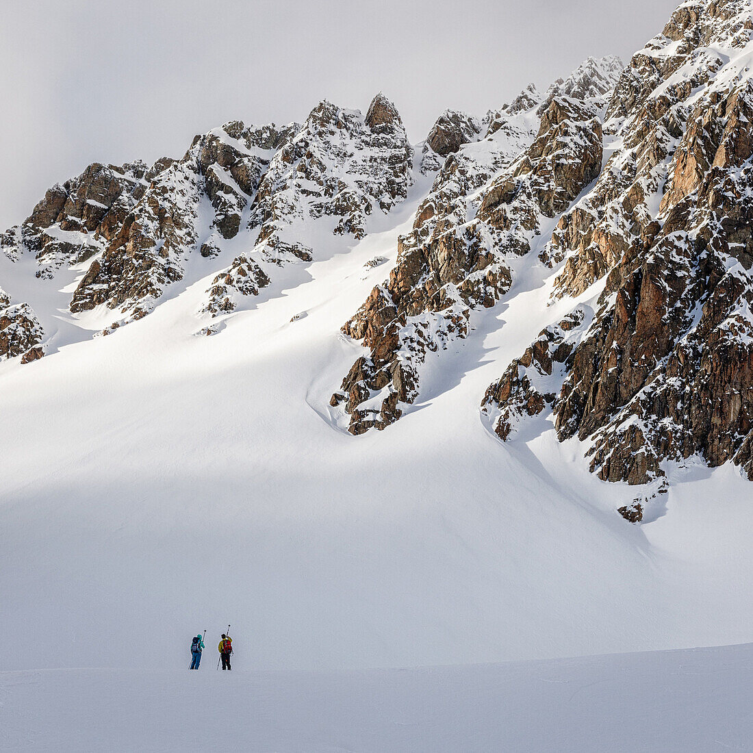 Zwei Skitourengeher begutachten einen felsdurchsetzten, unverspurten Hang, Tuoi Hütte, Scoul, Silvretta, Schweiz