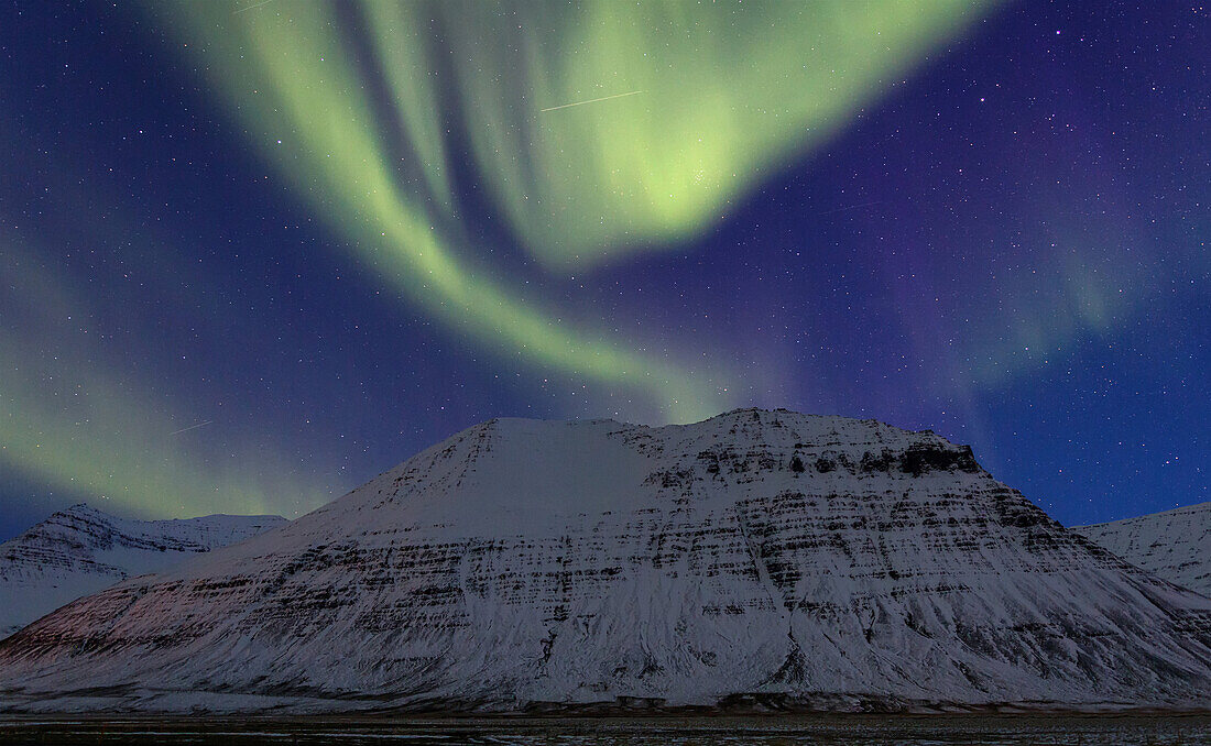 Polar lights over a snow covered mountain in the Westfjords, Iceland