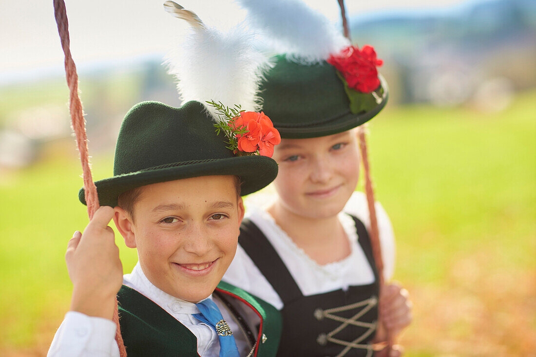 Kids in  Traditional bavarian clothes on a swing, Ammerland, bavaria, Germany