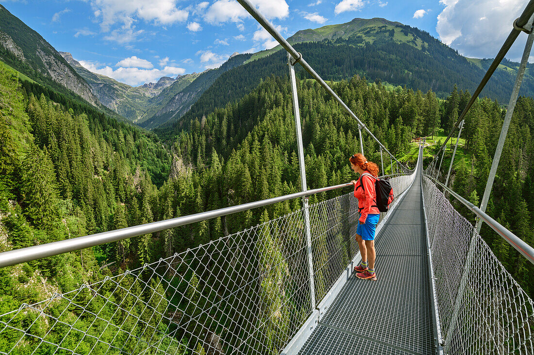 Frau steht auf Hängebrücke und blickt in die Tiefe, Holzgau, Lechweg, Lechtal, Tirol, Österreich