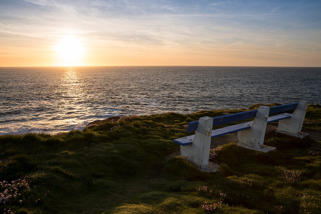 Eine Parkbank um den Sonnenuntergang an den Klippen von Kilkee und dem Atlantischen Ozean zu genießen, Kilkee, County Clare, Irland, Europa