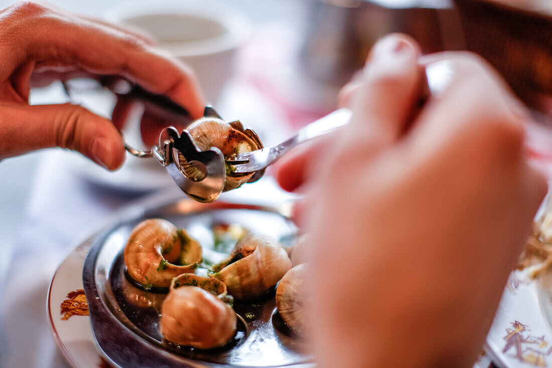 Ein Mann isst Escargots (Schnecken) auf dem Tisch in La Mère Catherine Restaurant, Place du Tertre, Montmartre, Paris, Frankreich, Europa