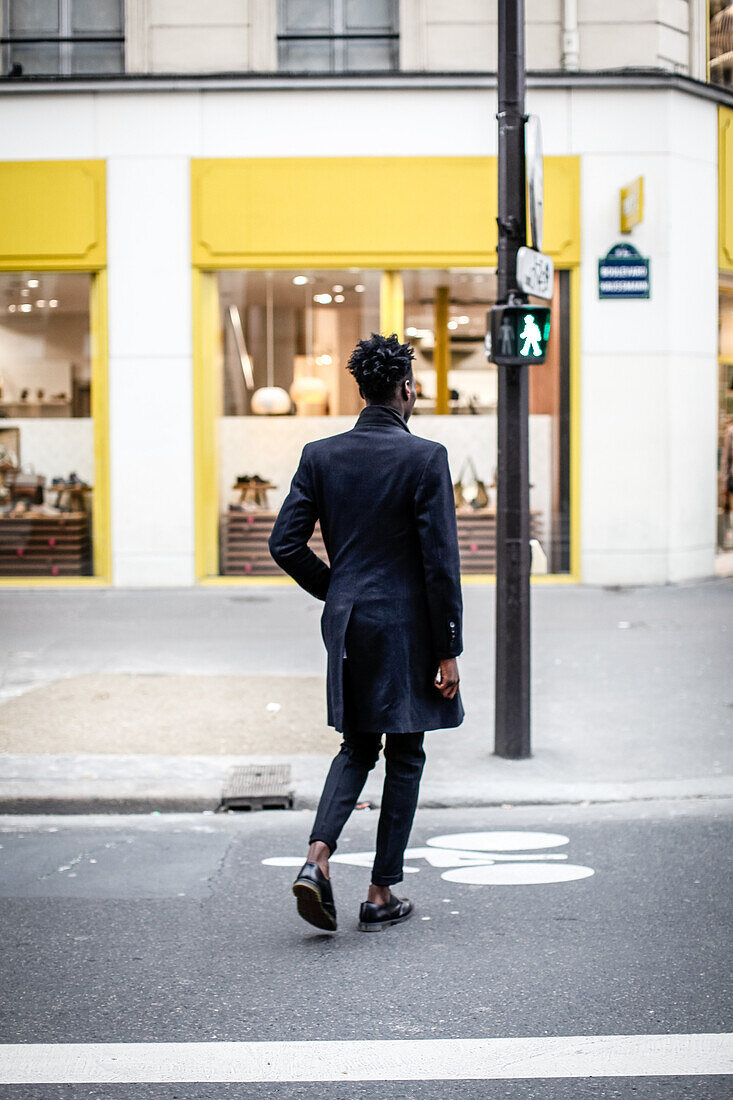 An African American man is walking across the street, Paris, France, Europe