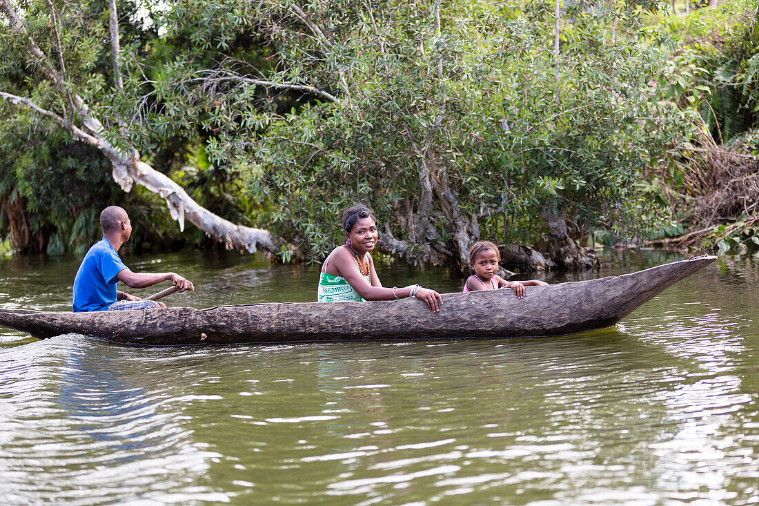malagasy family paddling in dugout canoe on the Canal de Pangalanes, East Madagascar, Africa