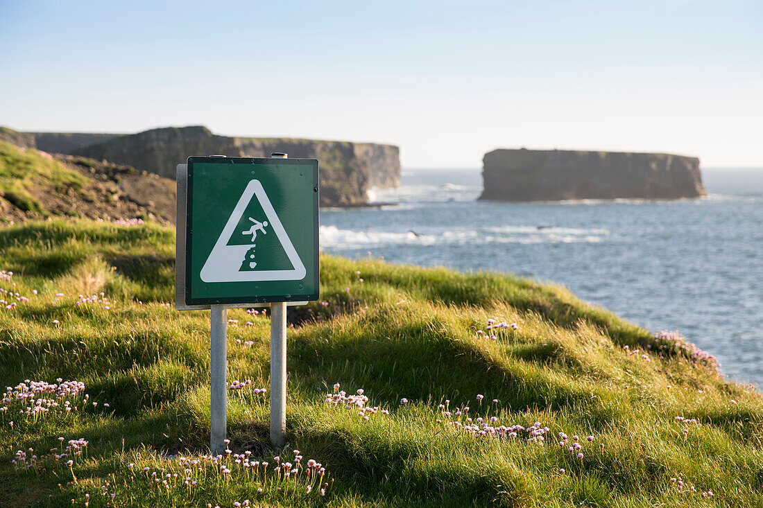 Achtung! Der Rand der Klippe ist nicht durch Zäune oder Mauern gesichert und dieses Schild warnt die Wanderer entsprechend, Kilkee, County Clare, Irland, Europa
