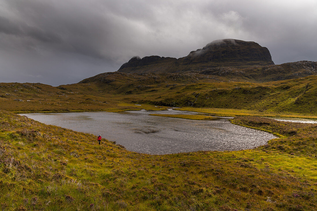 A hiker under the Suilven, Inverpolly Nature Reserve, Highlands, Scotland, UK