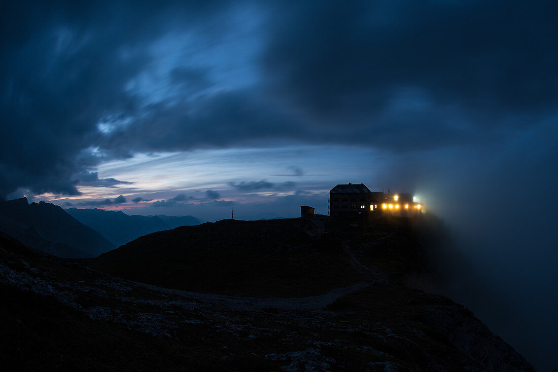 Hell erleuchtete Fenster des Watzmannhaus in der Abenddämmerung, Berchtesgadener Alpen, Berchtesgaden, Deutschland