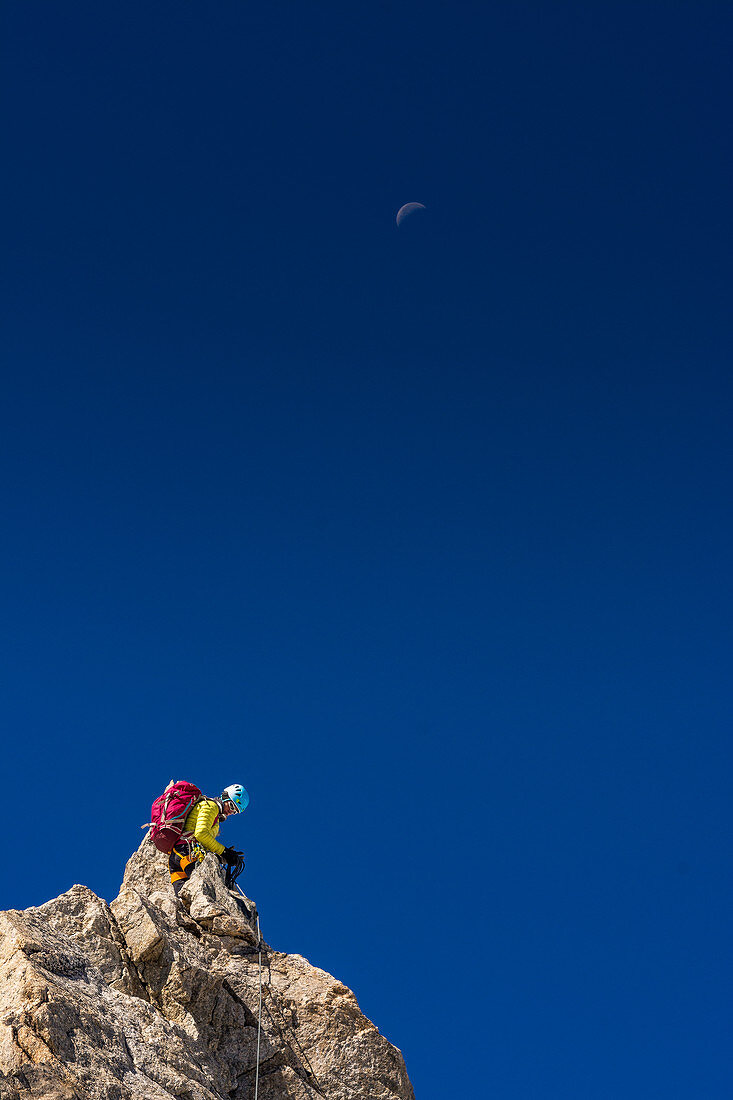 Climber on rock in front of blue sky, ridge at Dome de Rochefort, Grandes Jorasses, Mont Blanc group, France
