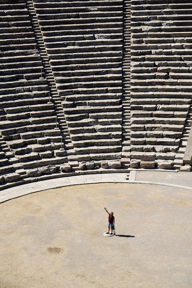 WOMAN STANDS IN ANCIENT THEATER OF EPIDAURUS, ARGOLIS, PELOPONNESE, GREECE
