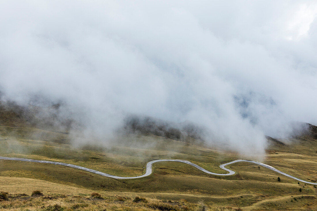 Kurvige Straße und Hochnebel am Bergpass Giau, Südtirol, Italien