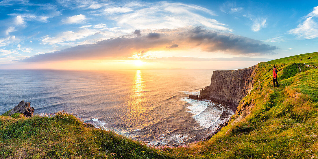 Man looking at Sunset at the Cliffs of Moher, County Clare, Munster province, Republic of Ireland, Europe. 