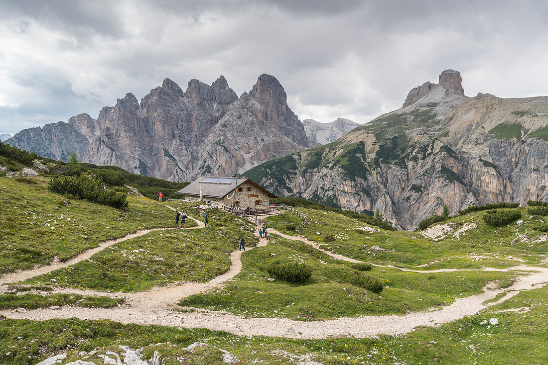 People hiking on the trails near Grava Longa hut, with Mount Rudo, Rondoi and Scarperi tower in the background. Sesto Dolomites, Trentino Alto Adige, Italy.