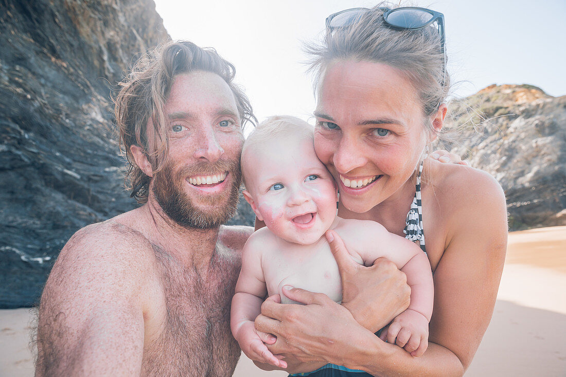 Junge Familie am Strand in Nordspanien lacht in die Kamera