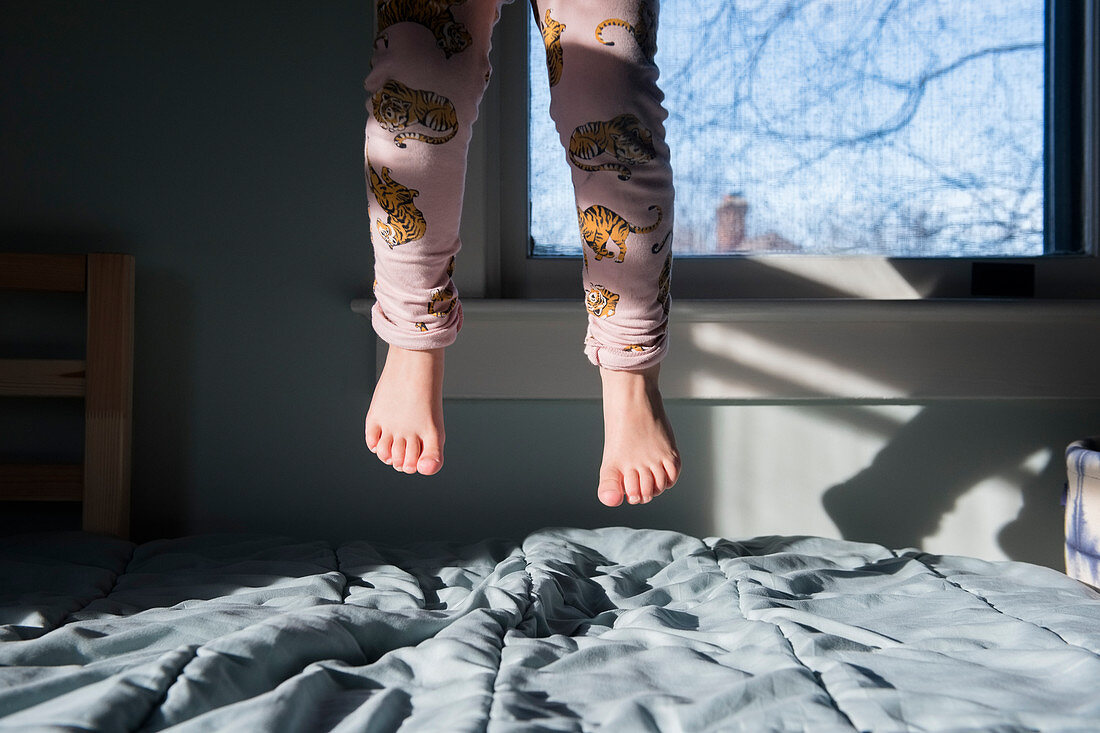 Beine des Mädchens, springend auf einem Bett