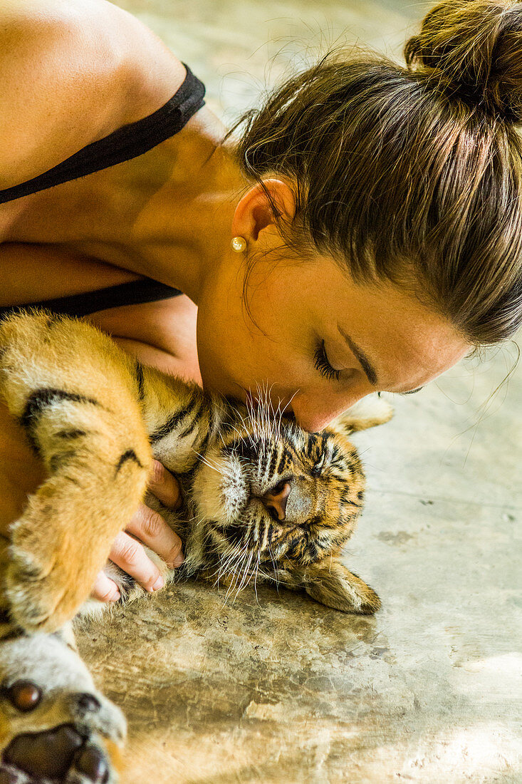 Eine Frau küsst Tigerjunges