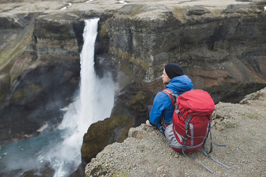 Wanderer mit Rucksack auf Klippe durch Haifoss-Wasserfall in Island