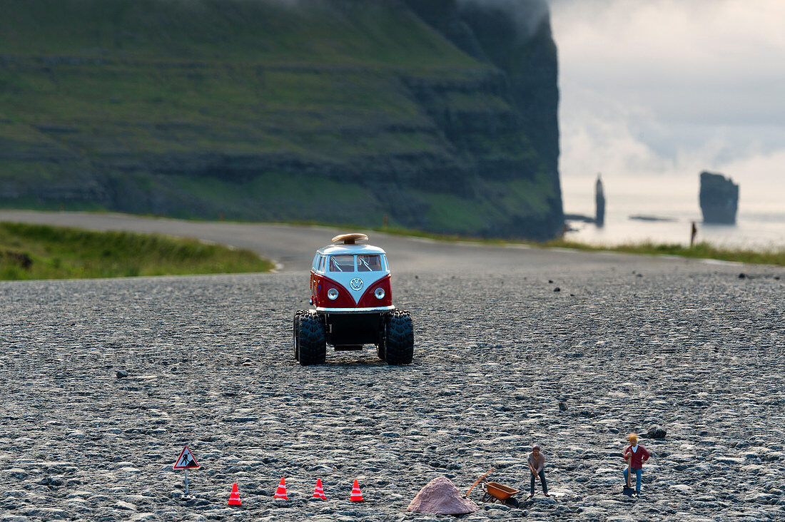 Scale models of vintage camper and figurines on asphalt road, Eysturoy island, Faroe Islands, Denmark