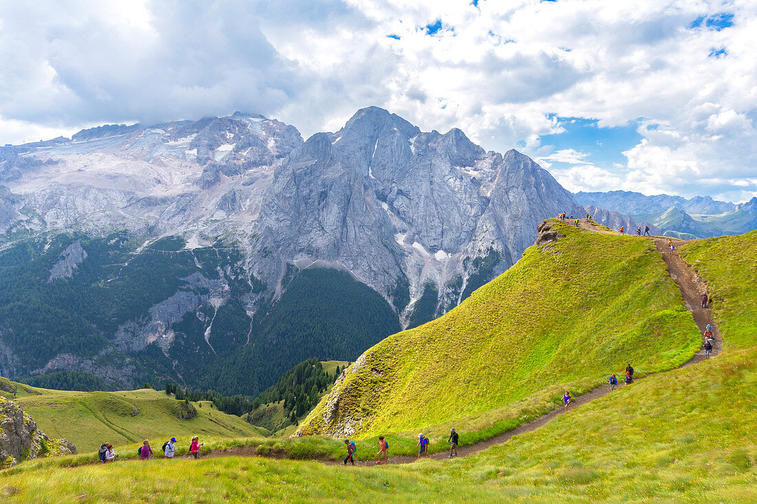 Hikers walks on Viel del Pan Path near Pordoi Pass, Fassa Valley, Trentino, Dolomites, Italy, Europe.