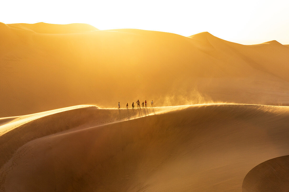 People walking on the edge of a sand dune at sunset,Walvis Bay,Namibia,Africa