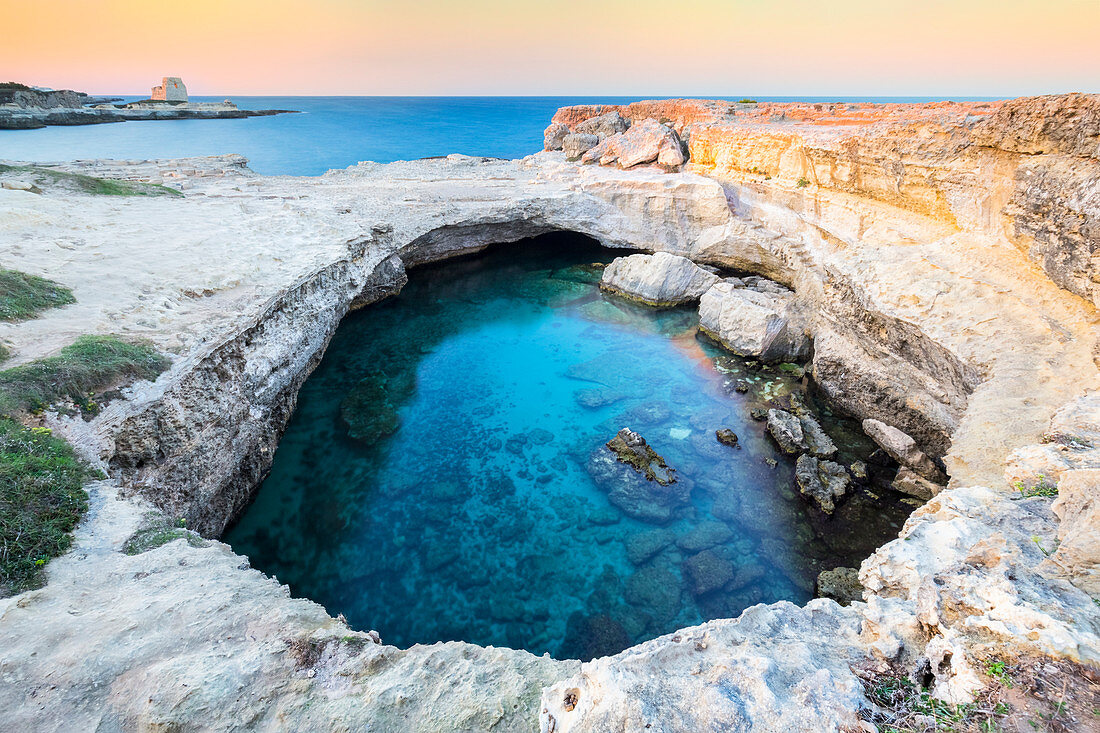 View of a sunset at the Grotta della Poesia cave in Roca Vecchia, near Torre dell'Orso. Melendugno, province of Lecce, Salento, Apulia, Italy.