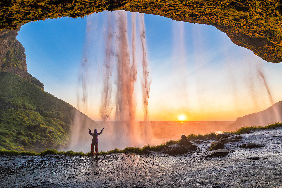 A girl behind the Seljalandsfoss waterfall at sunset (Skogar, Southern Region, Iceland, Europe) (MR)